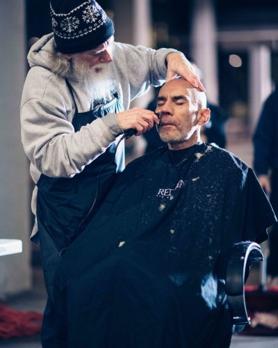 Barber giving grooming services to a man in need.